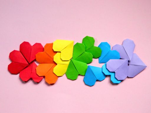 A top view of colorful heart-shaped papers on a white background - pride flag concept