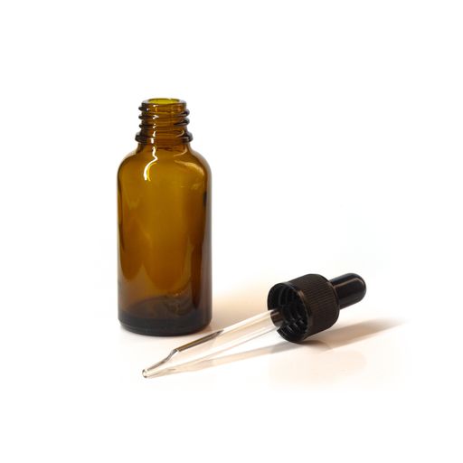 A brown glass bottle with the dropper next to it on a white surface
