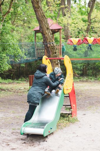 Woman standing by a slide equipment with a toddler boy at a playground in the Nowe Zoo