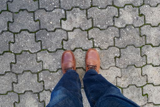 A high angle shot of a person's legs on a patterned cement tiles