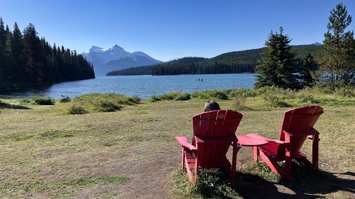 A woman sitting in a chair in front of the Maligne Lake in Jasper National Park, Alberta, Canada