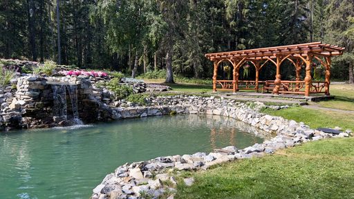 The wooden gazebo with a pond surrounded by green vegetation. Cascade Garden in Banff, Alberta, Canada.