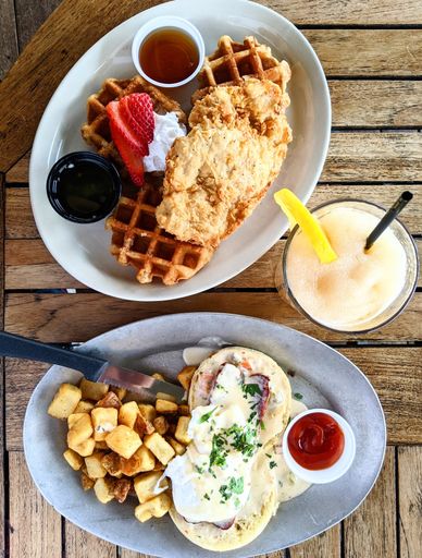 A top view of brunch meal with chicken and waffles and eggs benedict