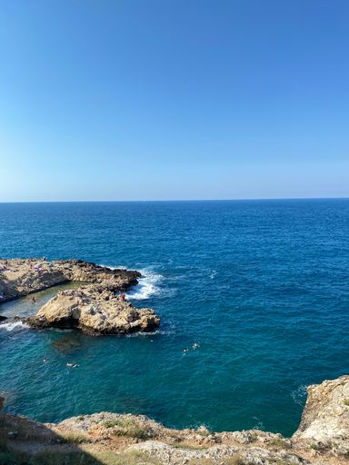 A vertical shot of  tourist swiminng in arocky beach