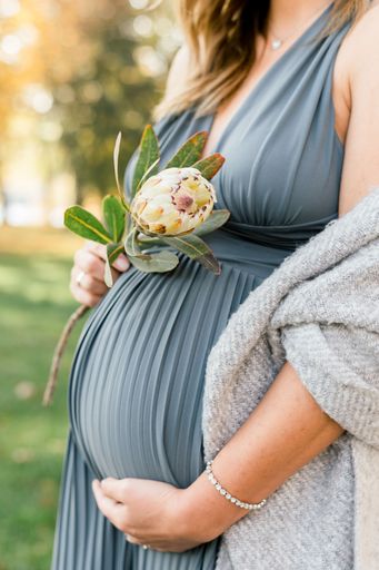 A vertical shot of a pregnant woman holding a flower in Germany
