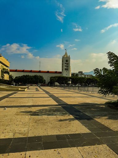 A vertical shot of a building with a tower and wide space during a sunny day