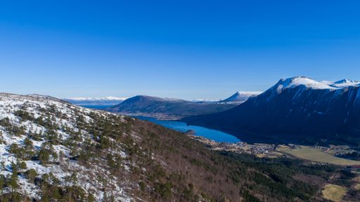 An aerial view of snow covered Norwegian mountain landscape surrounded by water
