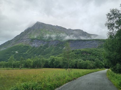 The cloudy sky over the rocky mountain captured from the narrow asphalt road in Norway