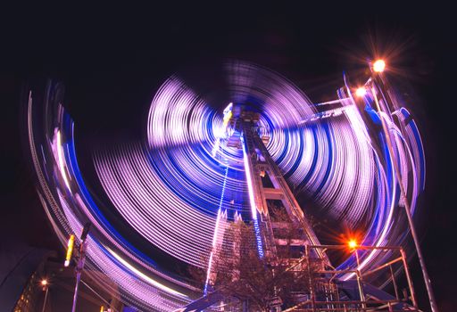 Long exposure night photography of a ferris wheel at an amusement park.