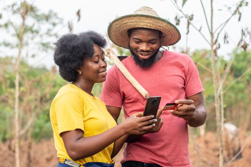 excited african farmers using a phone and credit card