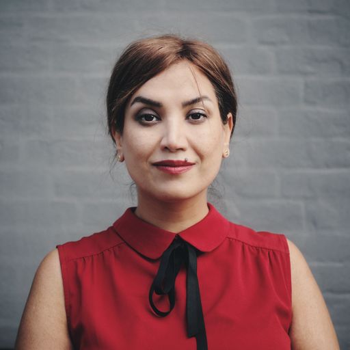 A beautiful Turkish woman chemist in a red outfit against gray wall background