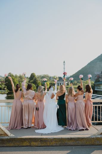 A vertical shot of a bride and her bridesmaids standing on a bridge and holding bouquets