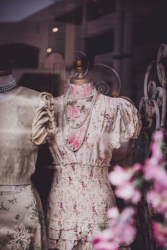 A vertical shot of a beautiful vintage dress with a floral pattern and a pearl necklace on the display