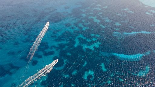 An aerial of two motor boats drawing water trails on a beautiful turquoise seascape