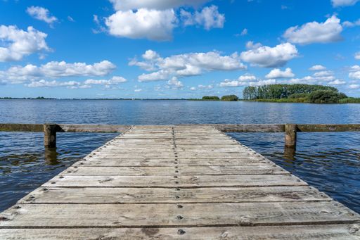 A beautiful shot of an old wooden jetty made of planks under a blue cloudy sky