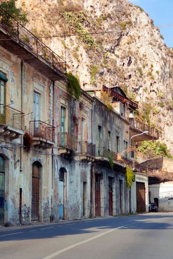 A line of old houses with withered walls by a mountains
