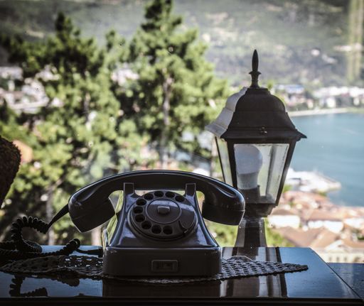 An old vintage black phone on the table at the window