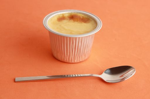 A delicious egg flan in an aluminum container and a spoon