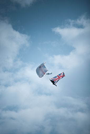 A lover of extreme sports skydiving with a parachute with the UK flag from the cloudy sky