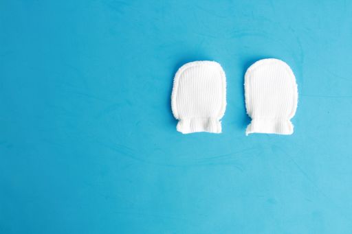 An overhead shot of white wool mittens for baby