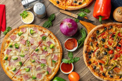 A top view of different pizzas on a wooden surface with different ingredients