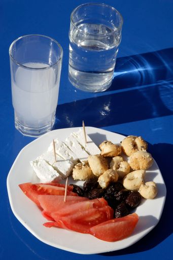 A vertical shot of a plate with appetizers and glasses of water on the blue table