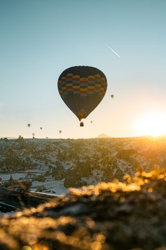 A vertical shot of colorful hot air balloons in the sky with the evening sunset in the background