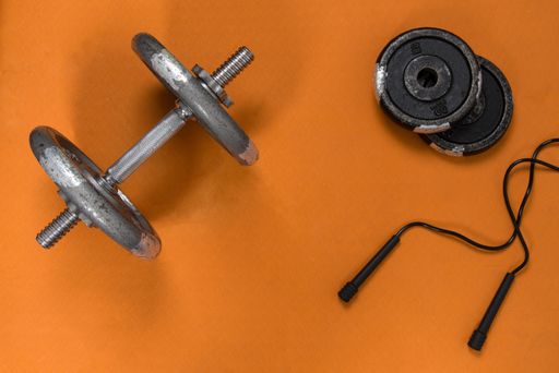 A top view of an exercising rope with dumbbells on an orange yoga mat