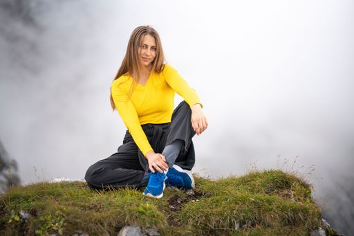 A young girl sitting on the top of a mountain against white fog and smiling