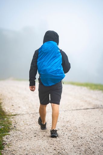 A man with a backpack walking on a cloudy and foggy day