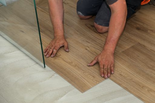 A close up shot of a worker installing new vinyl tile floor