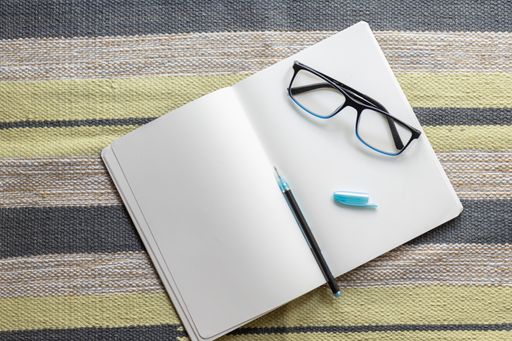 A top view of an opened notebook with pen and eyeglasses on it