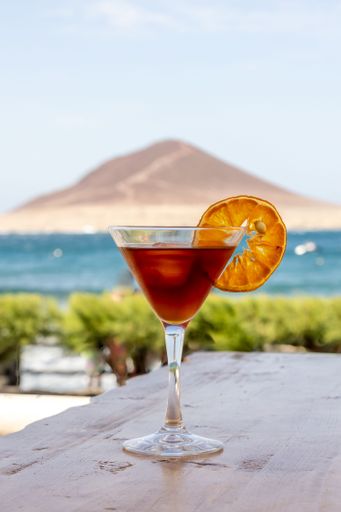 A vertical closeup of a blood and sand cocktail, mixed drink in a glass decorated with a lemon slice