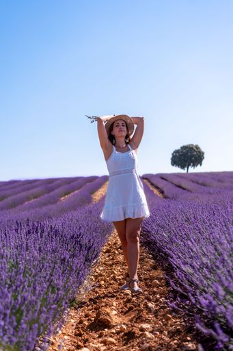 A vertical shot of a caucasian woman in a summer lavender field