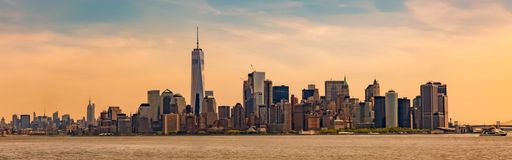 A panoramic shot of a New York City cityscape with high skyscrapers on the shore of a lake under the colorful sky