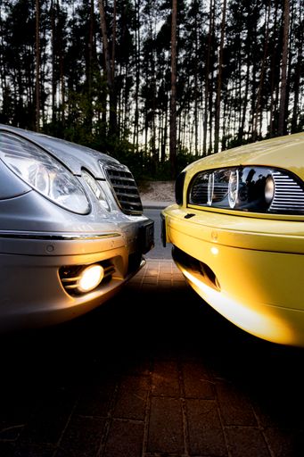 A vertical shot of two cars facing each other with lit headlights