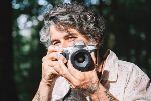 A portrait of a man looking behind the viewer of a vintage camera