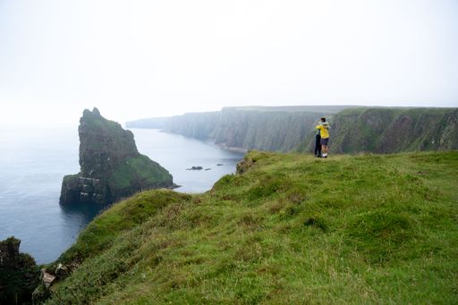 The people standing and hugging in the green field near the Duncansby Head mainlands in Scotland