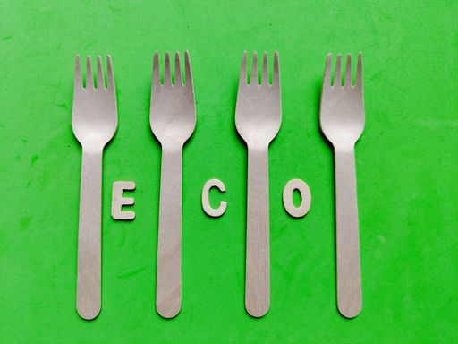 A top view of wooden forks on a green background and the word eco
