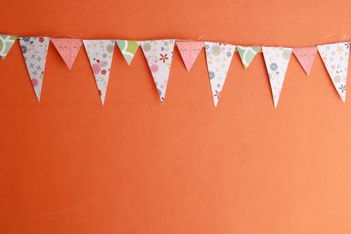 A string of party buntings hanging on an orange wall