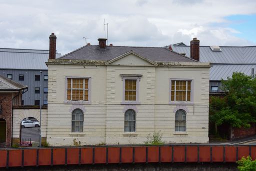 A cozy brick house with white walls and a dark roof under a cloudy sky in England