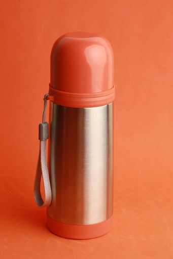 A vertical closeup shot of an orange thermos