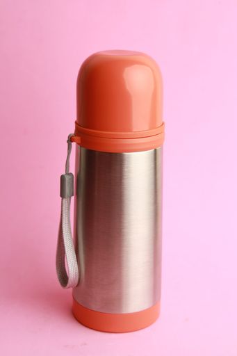 A vertical shot of an orange thermos on a pink background