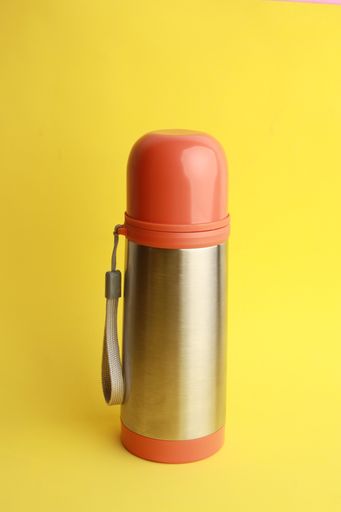 A close up shot of an orange thermos to keep the drink hot