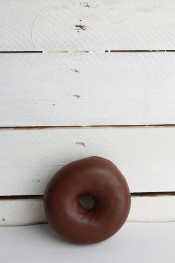 A closeup shot of a chocolate bagel on a white wooden surface