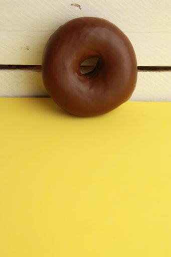 A closeup shot of a chocolate bagel on a yellow background