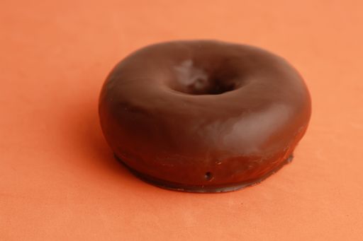 A closeup shot of a chocolate bagel on an orange background