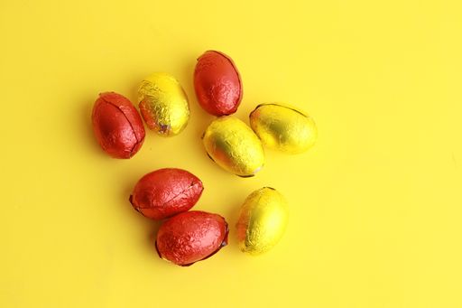 A top view of colorful chocolate Easter egg candies on a yellow background