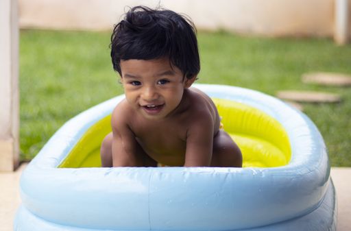 A horizontal shot of a cute little boy having fun in the inflatable pool