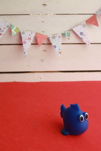 A high angle shot of a cute toy of a blue fish-shaped bathtub on an orange background